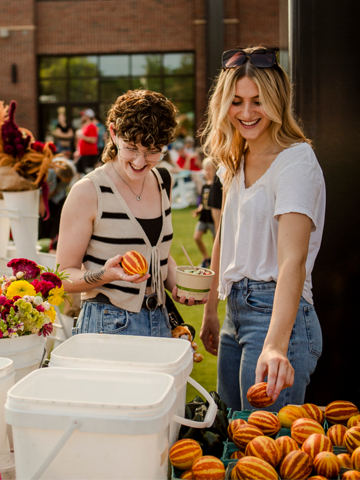 two women looking at produce at an outdoor farmers market